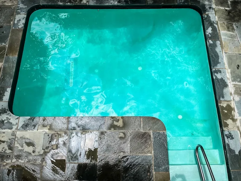 Small modern spa with turquoise water and stone patio surround