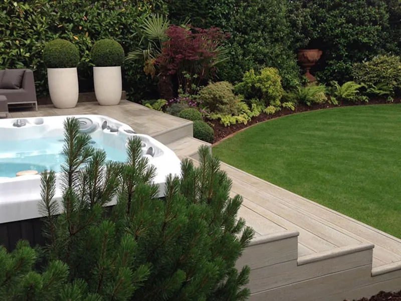 Family hot tub on a wooden deck surrounded by lush garden